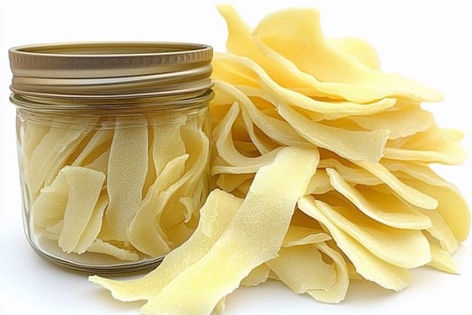 Dried mango slices are arranged artfully around a glass jar filled with the same dried fruit. Their light color and smooth texture highlight their natural sweetness.