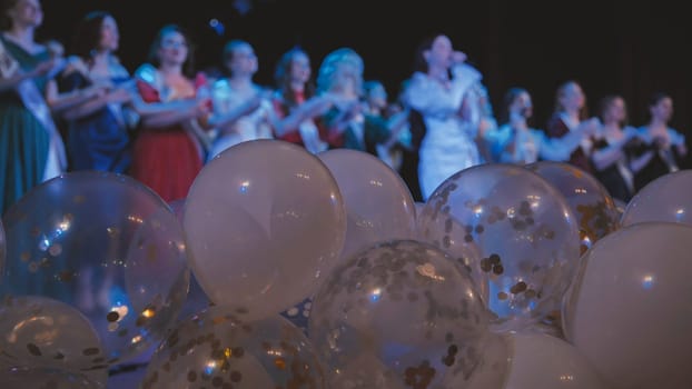 White and transparent balloons with confetti wait on a stage for the arrival of celebrating graduates after their school ceremony
