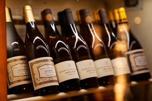 Collectible bottled wines stand on shelves in a wine refrigerator in storage. High quality photo