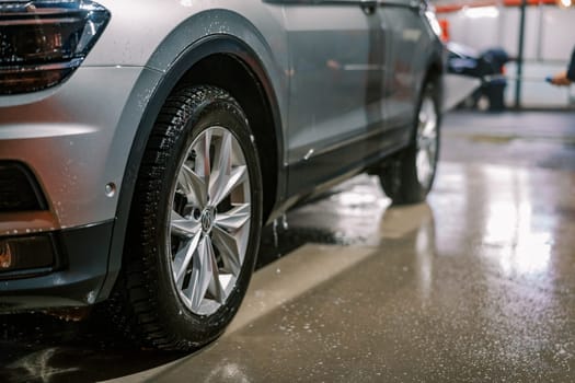 Soap spray drips from car doors and wheels onto the car wash floor. High quality photo