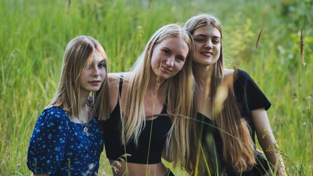 Teenage friends laughing together, spending carefree moment amid golden grassland, sharing close friendship