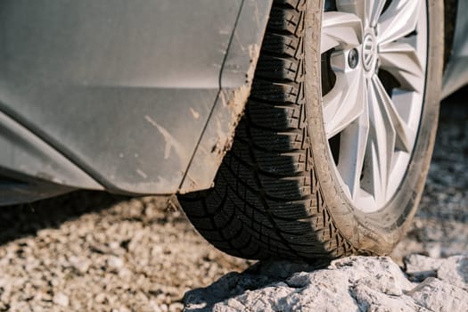 Car stands with a wheel on a rocky ledge with sagging. Close-up. High quality photo