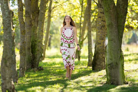 Young woman is enjoying a sunny day as she walks barefoot among trees