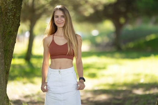 Sporty young woman is smiling in a park during a sunny day