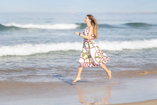 Young woman is running along the beach, enjoying her summer vacation