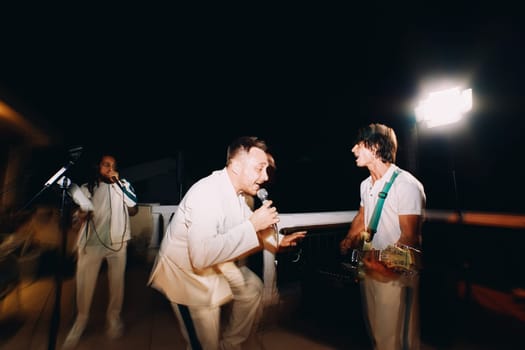 Male group sings on a night stage under floodlights. High quality photo