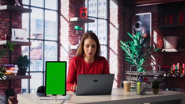 Woman organizing and planning activities on the agenda next to chroma key, overseeing time management for the schedule by using online tools as weekly planner and digital calendar. Camera B.