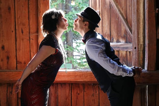 A pair of lovers in 20s retro style kissing in front of a window