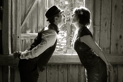 A pair of lovers in 20s retro style kissing in front of a window