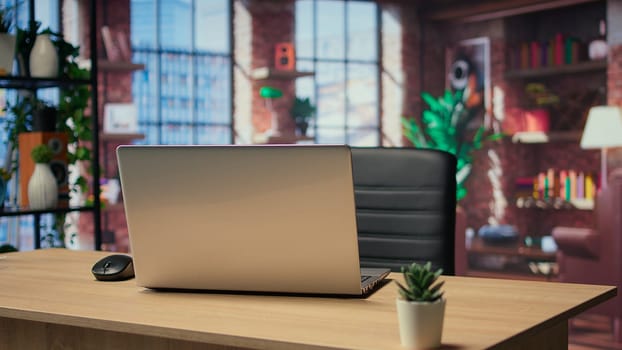 Empty modern studio apartment with an office desk used for freelancing, stylish industrial urban space decorated with trendy furniture and wooden floors. Minimal studio with indoor plants.