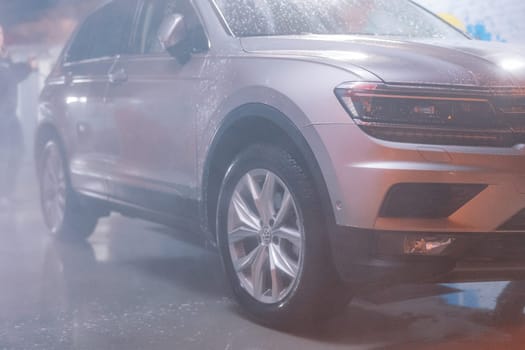 Wet car in a thick spray stands at the car wash. High quality photo