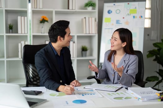 In a vibrant office setting, two colleagues are engaged in an animated conversation, exchanging insights and promoting teamwork.