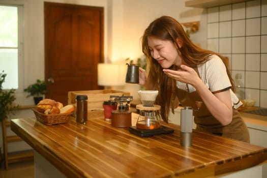 Young woman savoring the scent of coffee during home brewing process.