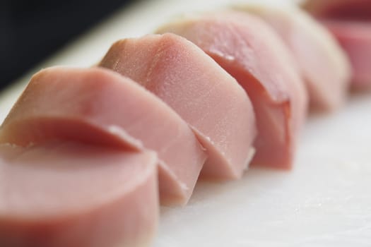 Brightly colored slices of fresh tuna lay neatly on a cutting board.