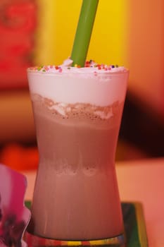 Sweet chocolate drink served in a tall glass with colorful sprinkles.