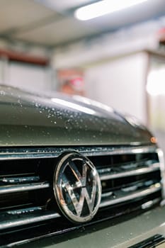 Wet hood of a car with a Volkswagen sign. Cropped. High quality photo