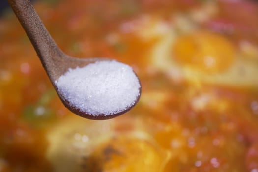 Chef adds salt to enhance flavor in a bubbling pot of stew.