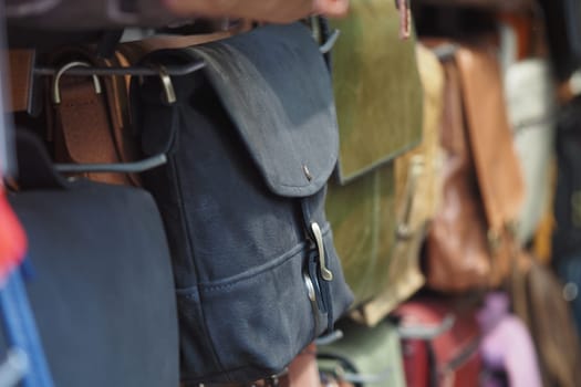 Various handcrafted bags hang on display in a vibrant market setting.