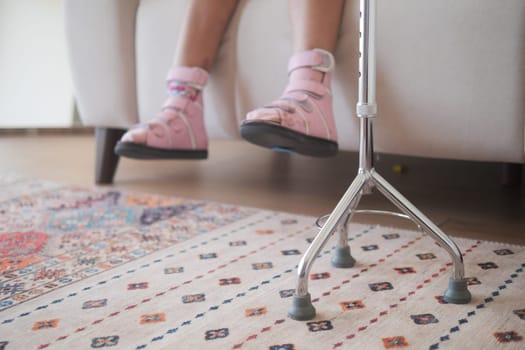 A young child relaxes on a couch, using crutches for support and comfort.