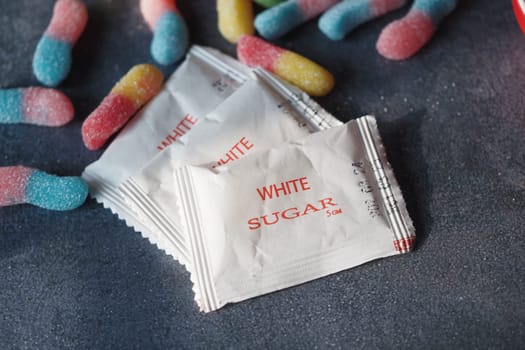 Packets of sugar are arranged with assorted gummy candies nearby.