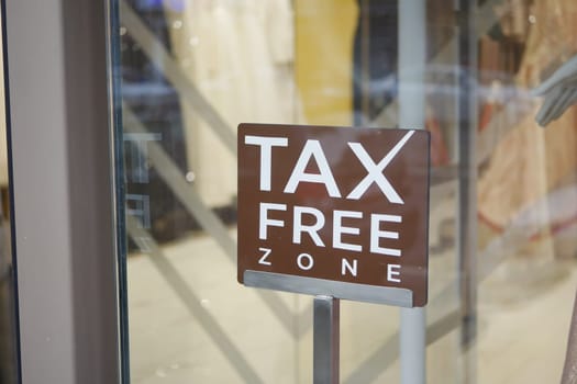 Sign indicating a tax free zone at a retail store in a city environment.