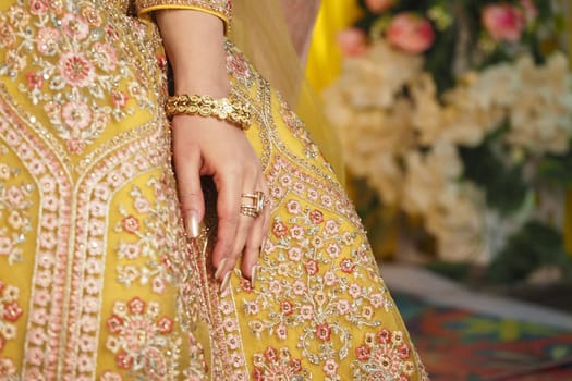 A close-up view of a bride's hand holding her ornate dress at a wedding.