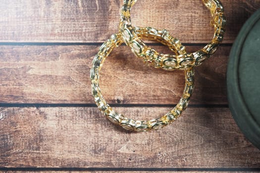 Golden bangles are placed on a rustic wooden table, highlighting their design.