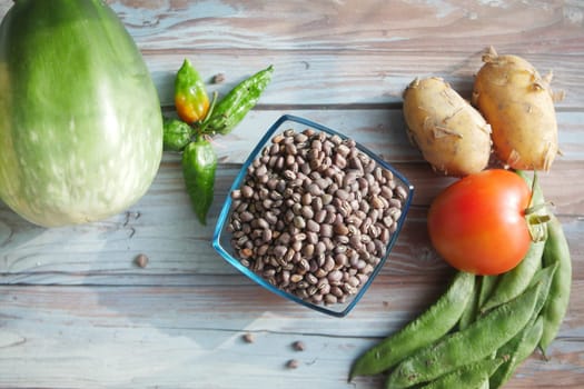 Assorted vegetables and beans arranged on a rustic wooden table.