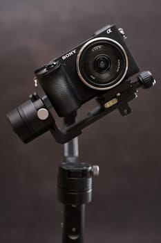 Digital mirrorless camera Sony A6000 stands tilted on a steadicam on a black background. High quality photo