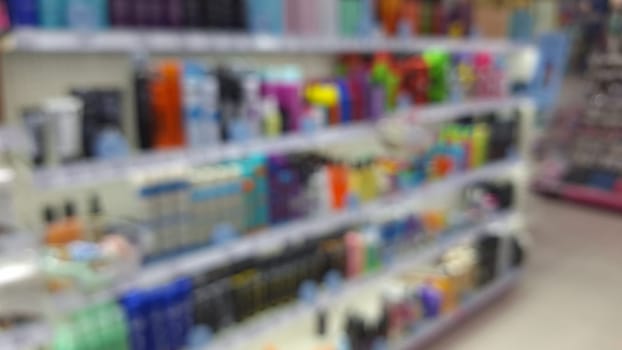 Blured view of Variety of haircare products on shelves in a store aisle.