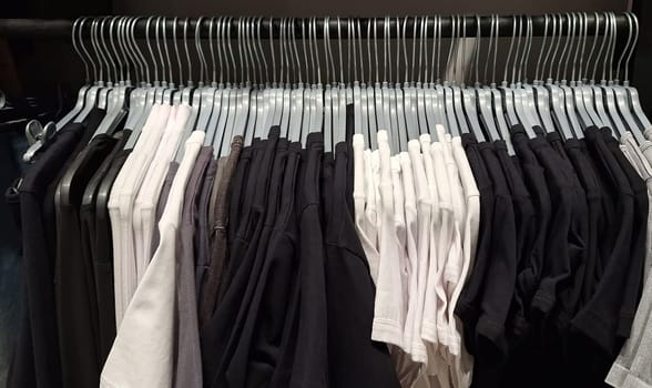 Black and white t-shirts on hangers in closet display.