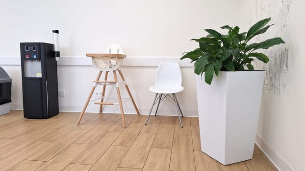 Modern waiting room with high chair, white chair, and potted plant.