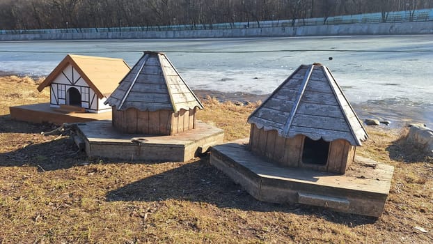 Wooden duck houses by frozen lake in winter sunlight.