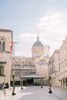 Colorful flags flutter in the wind on Stradun Square near the Cathedral of the Virgin Mary. Dubrovnik, Croatia. High quality photo