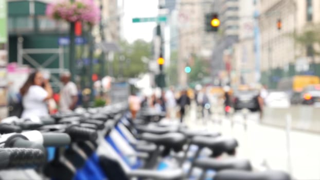 New York City Manhattan Downtown street or Midtown avenue crossroad intersection. Urban road traffic in USA. Defocused people pedestrians in United States. Blue rental bikes, sharing bicycles station.