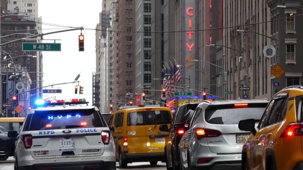 New York, United States - 10 Sept 2023: Police patrol car, Radio City Music Hall. USA NYPD 911, Manhattan Midtown street. American cop auto siren light, 6 avenue. Urban road traffic scene. Yellow taxi