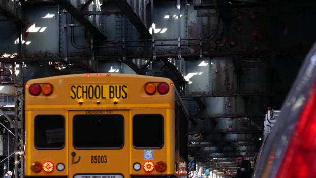 New York City, United States - 7 Sept 2023: Elevated subway above street. Metropolitan bridge over road, Queens. Overhead metro line. Car under railway track. Urban life. Yellow school bus, education