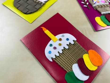 Charming handmade Easter card showcases delightful cake with candle and vibrant felt eggs. Ideal for sharing festive greetings and celebrating joyful spirit of Easter with loved ones