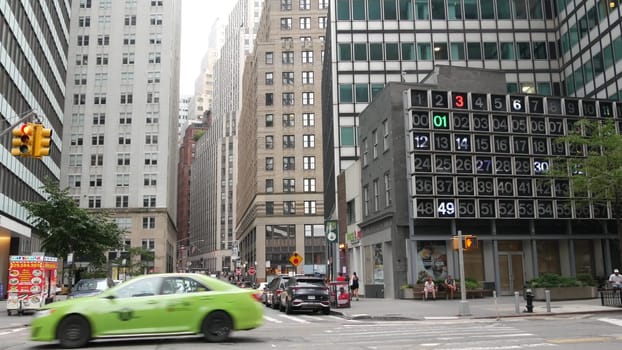 New York City, United States - 9 Sept 2023: Manhattan Downtown Financial District Water and John street crossroad intersection. USA road car traffic. Yellow taxi, people. Digital clock, bingo board.