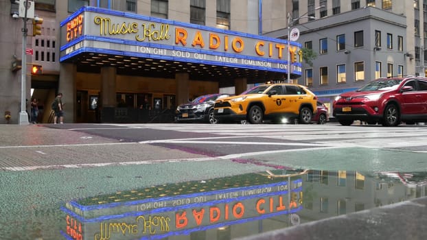 New York, United States - 10 Sept 2023: Manhattan Midtown street. Radio City Music Hall, Rockefeller Center, USA. People pedestrian, urban traffic, 6 Sixth Americas avenue crossroad, yellow taxi cab.