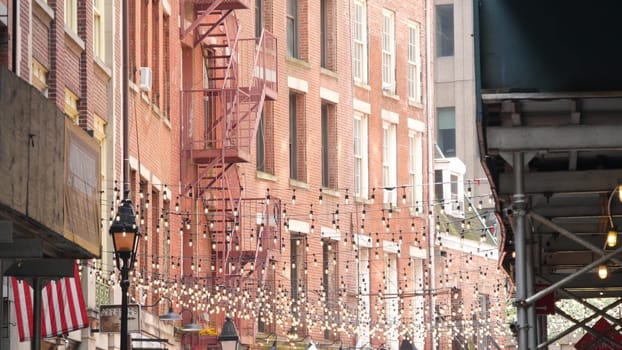 New York City, United States - 9 Sept 2023: Building architecture, house exterior. Real estate property, USA flag. Red brick facade. Manhattan downtown financial district, Stone st. Fire escape ladder