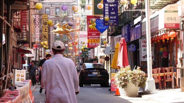 New York City, United States - 14 Sept 2023: Manhattan Chinatown Pell street. Chinese culture, ethnic district architecture, USA. Red brick buildings, round paper lanterns and hieroglyph signs. People