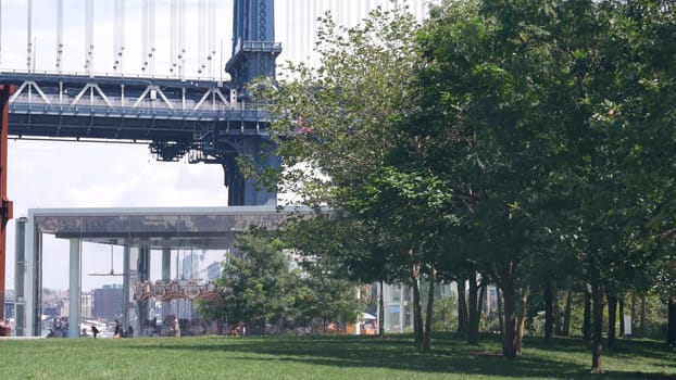 New York City, United States - 30 Aug 2023: Manhattan Bridge to Brooklyn Dumbo. Retro vintage Jane's Carousel, USA travel destination, tourist landmark. Cable-stayed bridge, old merry-go-round in park