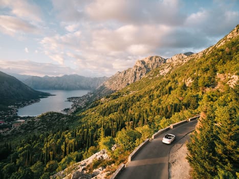 Convertible drives along the mountain highway above the Bay of Kotor. Montenegro. Drone. High quality photo