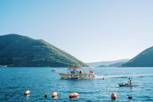 Tourist on a boat with an oar sails on the sea past an excursion yacht. High quality photo