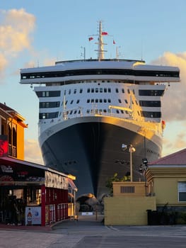 Puerto Rico, San Juan November 22. 2023 Front view of a large cruise ship docked impressively close to buildings in a vibrant Caribbean port town, captured at sunset with soft light and clear skies