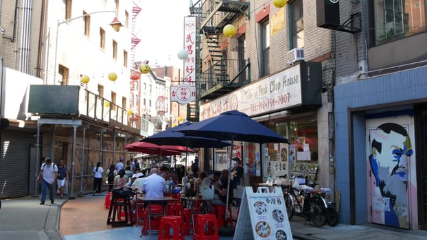 New York City, United States - 14 Sept 2023: Manhattan Chinatown Doyers street, chinese ethnic district building architecture, USA. People eating on tables on pavement sidewalk. Street food restaurant