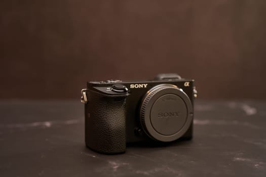 Sony A6000 digital mirrorless camera with a lens cap stands on a black marble table. High quality photo