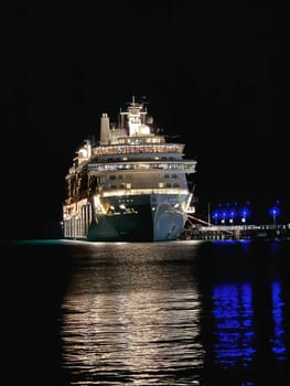 Puerto Rico, San Juan November 22. 2023 Illuminated cruise ship docked at a port under the night sky, with glowing lights reflecting beautifully on the calm ocean surface and surrounding pier.