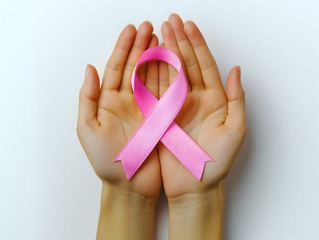 Two hands gently holding a pink ribbon, symbol of breast cancer awareness, care, and hope. Ideal for medical, charity, health campaigns, prevention efforts, and emotional support visuals.